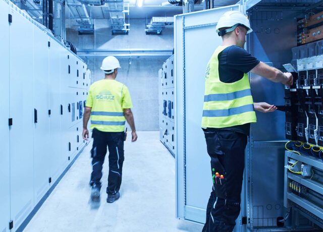 Zwei Techniker arbeiten an Schaltanlagen und prüfen elektrische Komponenten.