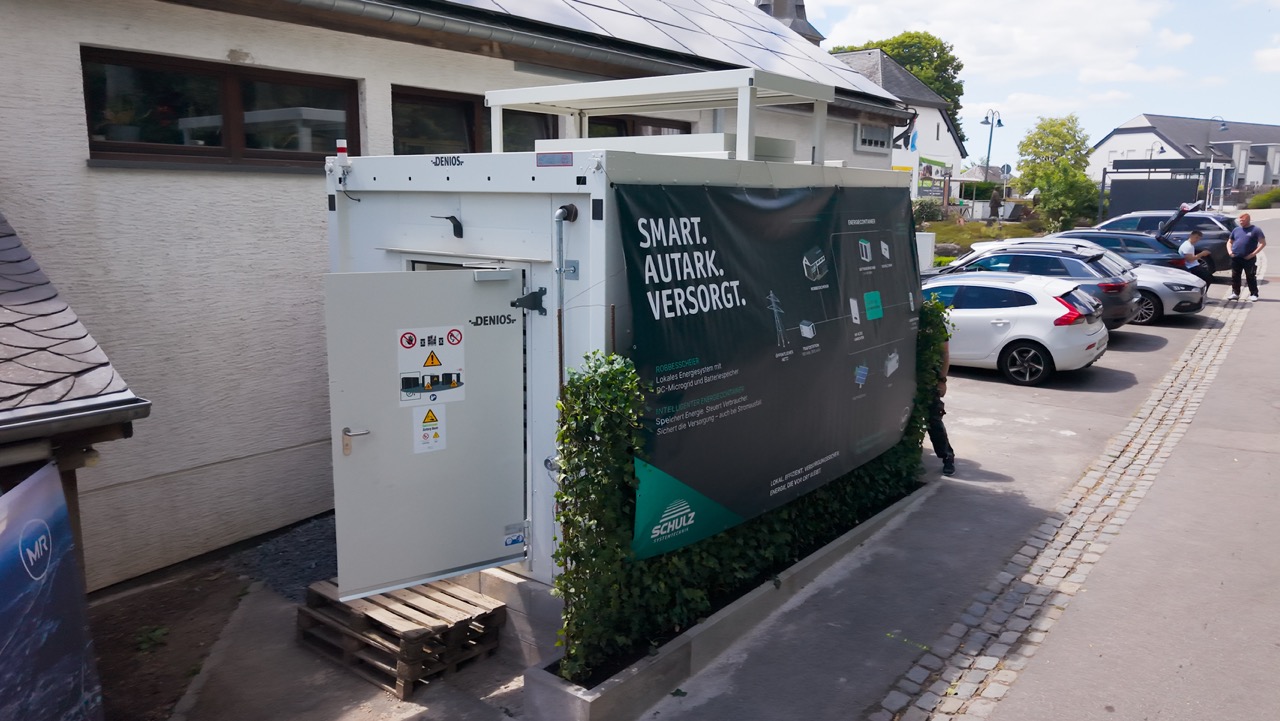 Außenansicht des Energiecontainers mit Banner zum smarten Energiesystem neben dem Gebäude.