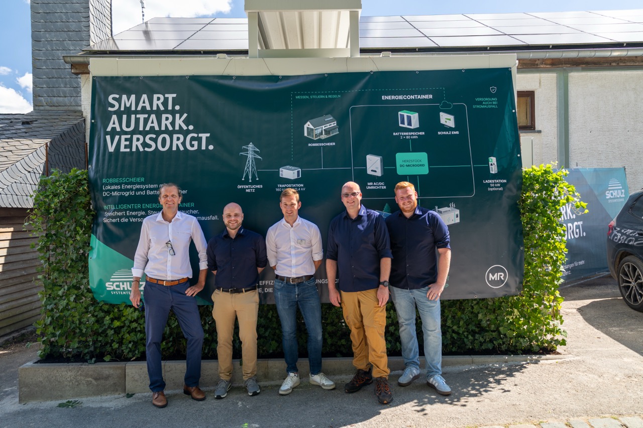 Projektteam steht beim Soft Opening vor dem Banner zum lokalen Energiesystem.