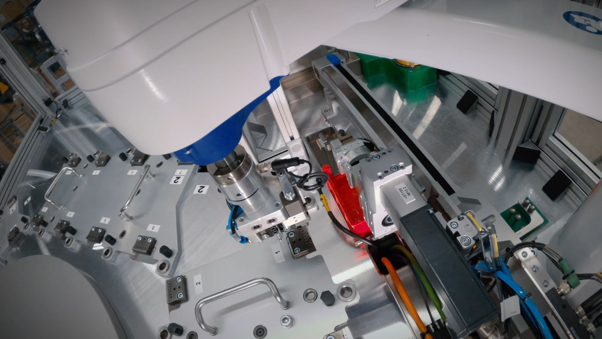 Greiferwerkzeug einer automatisierten Handhabungseinheit über einer Montagevorrichtung in einer Produktionsanlage.