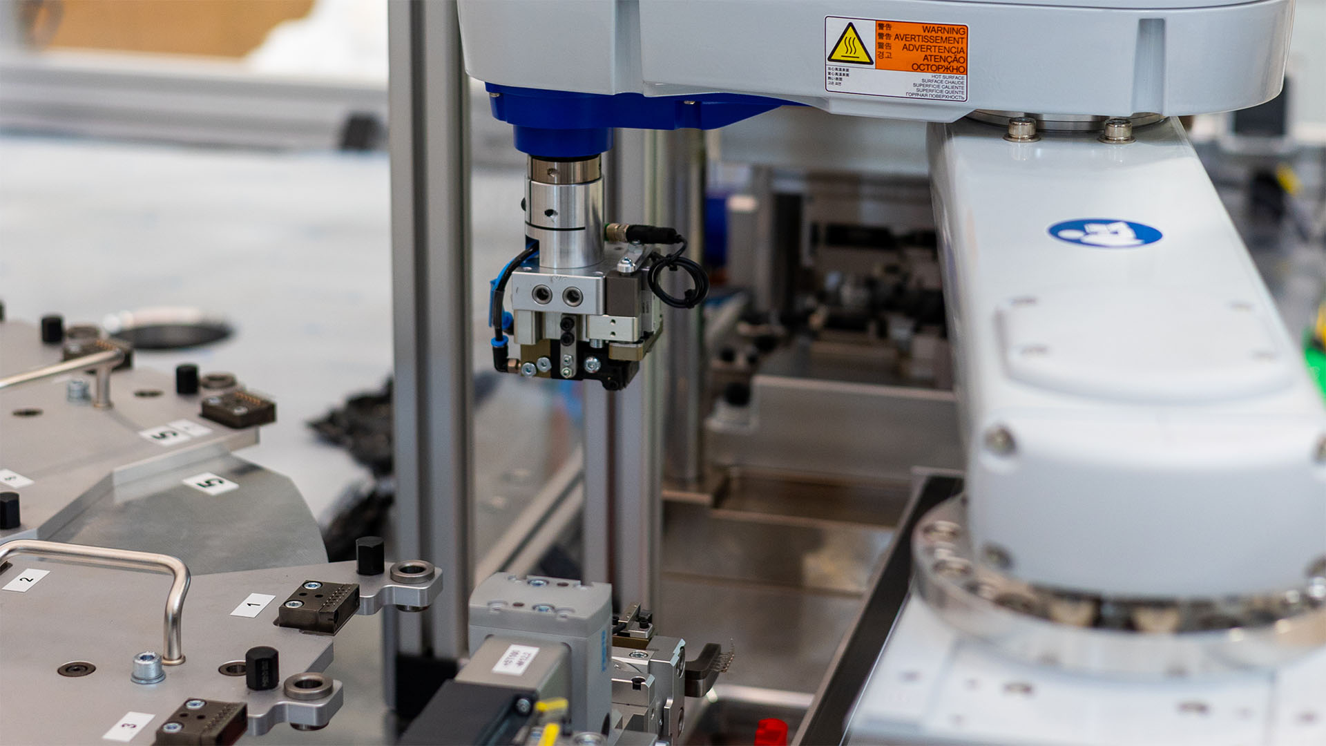 Greiferwerkzeug eines Industrieroboters mit Kabeln und Sensoren in einer automatisierten Produktionsanlage.