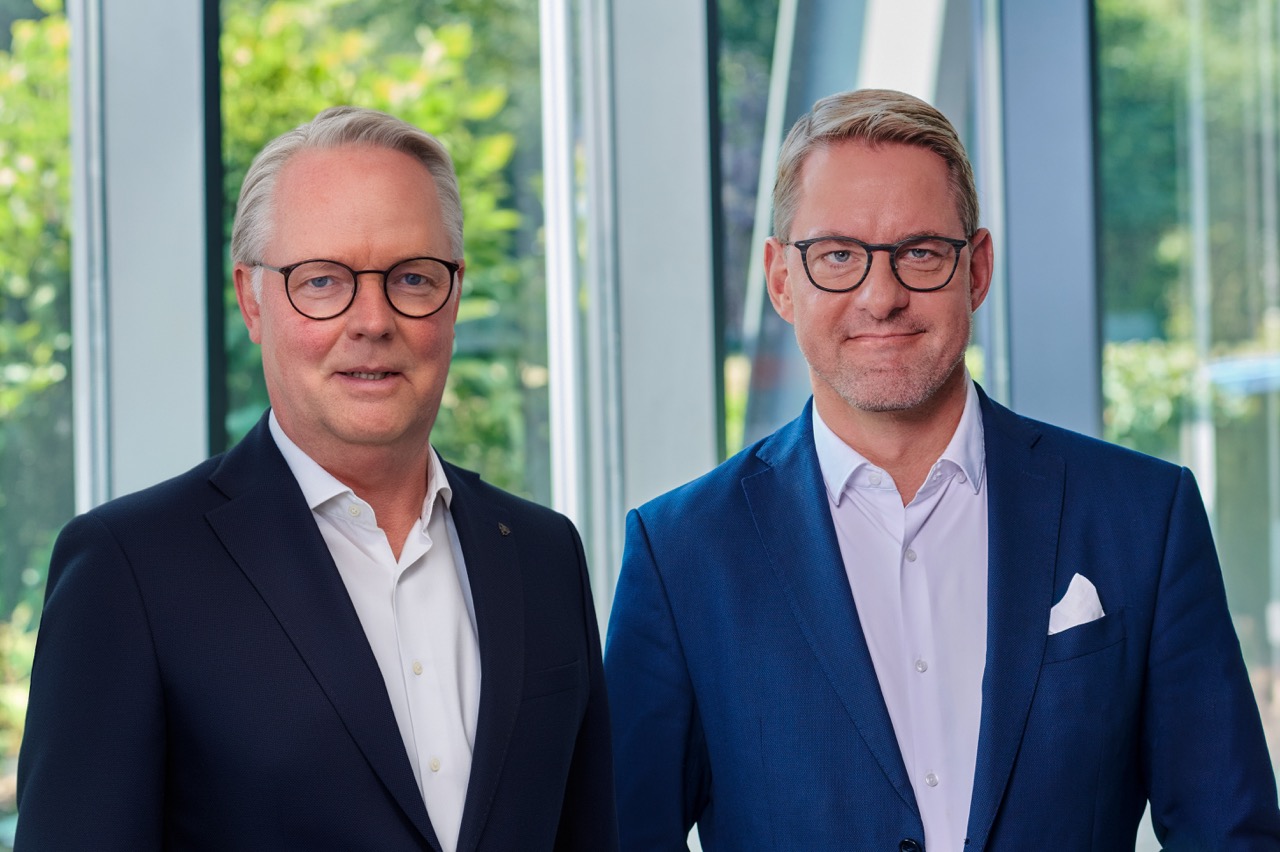 Von links: Jürgen Deters und Tobias Schulz (Geschäftsführung) im hellen Foyer, mit großen Fenstern und Pflanzen im Hintergrund.