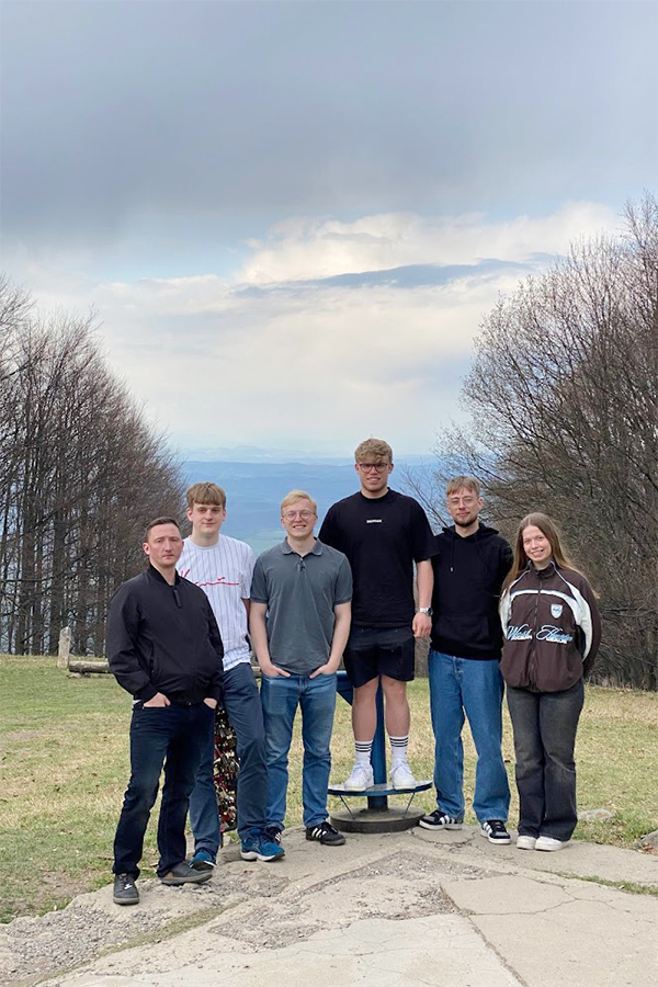 Sechs Personen stehen auf einer Wiese mit Bäumen und Landschaft in Ungarn.